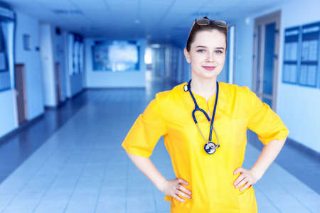 Doctor in yellow uniform in the hospital. Concept of a happy beautiful doctor girl with a smile.の写真素材