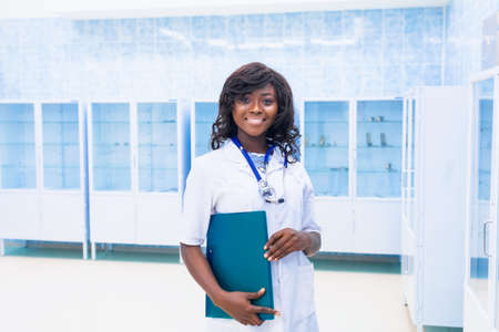 Portrait of a female doctor holding her patient diagram on a digital tablet in a bright modern hospital. African Surgeon Conceptの写真素材