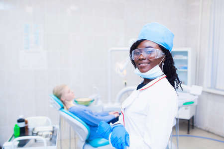 portrait of a black dentist girl in goggles in the dental officeの写真素材