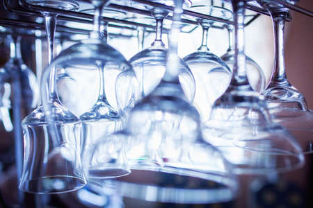 glasses for margarita. hang over the bar in the restaurant. A glass of wine and martini on the shelf above the bar in the restaurant. blue lights, blue background, night lifeの写真素材