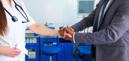 medicine, healthcare and technology concept - doctor with and male asian patient shaking hands at hospital. faceless backgroundの写真素材