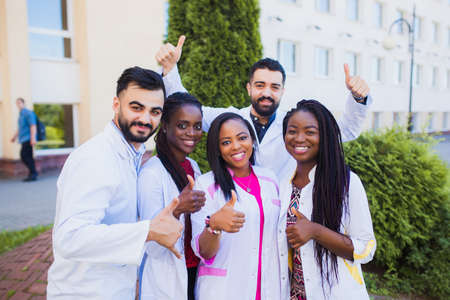 Group of cheerful African friends giving thumbs up. Happy interns physicians finish trainingの写真素材