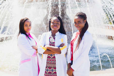 Medical staff. doctors, nurses, interns. A group of black Aurican female students on the background of a fountain on campusの写真素材