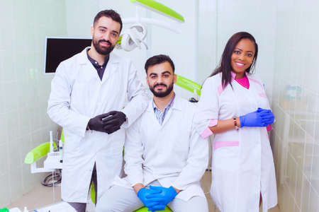 Friendly young multi ethnic personnel group graduated dentist and assistant Caucasian blond and...