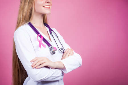 Female doctor with pink ribbon on pink background. The concept of cancer patients supportの写真素材