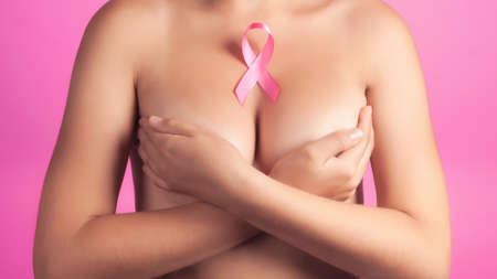 health, medicine, beauty concept - naked woman with Pink Breast Cancer awareness Ribbon. Support of patients with oncology.の写真素材