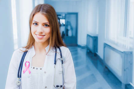 Doctor with a pink ribbon. Professional beautiful girl paramedic in the clinic. The concept of...