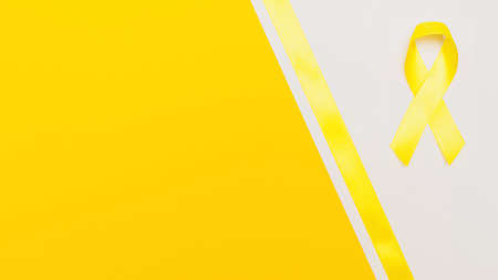 yellow cancer awareness ribbon with trail on white background. concept of health and medicineの写真素材