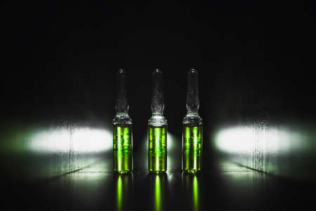 green ampoules on a black background. Narcotic acid. low key photo.の写真素材