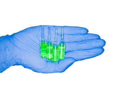 Green capsules ampoule held by hand in medical glove, isolated on white background. Chemotherapy