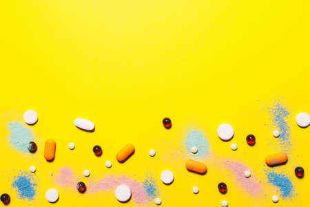 Yellow medical background. Multicolored pills top view. childhood diseases. place for text. Copy spaceの写真素材