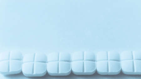 Top view of the Spilled white pills on the blue surfaceの写真素材