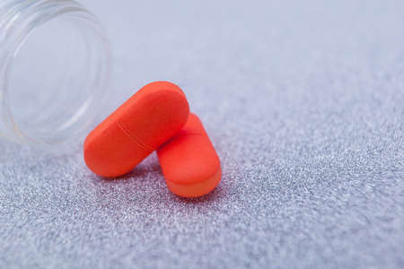 Two red capsules of medical pills isolated background