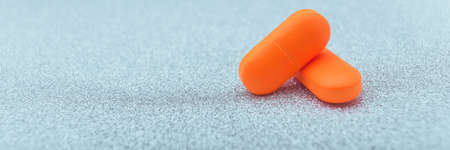 two red pills close up on blue glitter, sparkles, sparkling background copy space. Global healthcare...