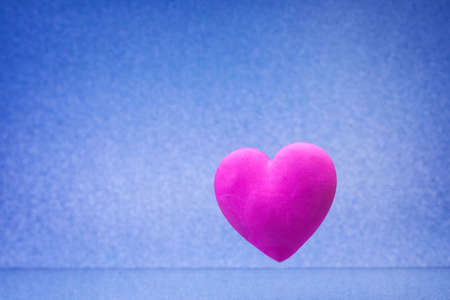 Plain blue background with little violet red heartの写真素材