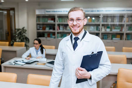 a medical student for textbooks. The study of surgery by a man in a tie in the library. Nurse. copy...