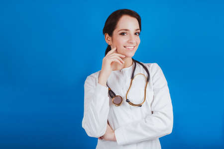 A young female doctor in white clothes on a blue background
