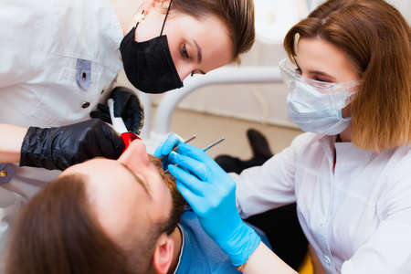 Young professional doctor dentist in a modern office with dental equipment. The concept of health insurance and free dental care. Prosthetics and installation of veneers.の写真素材