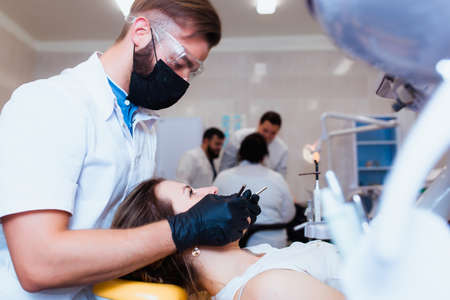Young professional doctor dentist in a modern office with dental equipment. The concept of health insurance and free dental care. Prosthetics and installation of veneers.の写真素材