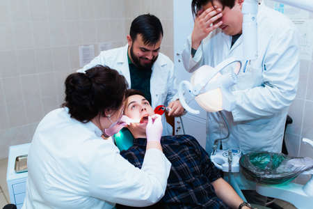 Medical University. Professional teacher dentist doctor treats teeth to the patient in the office on modern equipment. The concept of medical training and transfer of experience.の写真素材