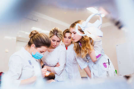 Medical University. Professional teacher dentist doctor treats teeth to the patient in the office on modern equipment. The concept of medical training and transfer of experience.の写真素材