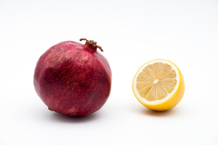 Red fruit of a pomegranate and yellow lemon on a white background isolated.の写真素材