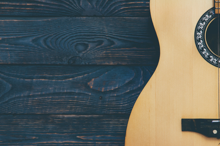 Acoustic guitar lies on a wooden textured background.の写真素材