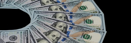 One hundred dollar bills are fanned out on a black background.