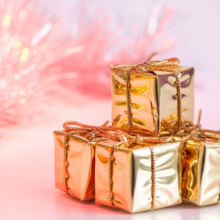 Merry Christmas, New Year, gifts in gold boxes on a background of pink and yellow bokehの写真素材