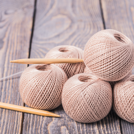 Balls of yarn and knitting needles for knitting on a wooden background.の写真素材