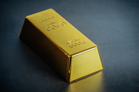 Gold bar ingot bullion on blue background. Located diagonallyの写真素材