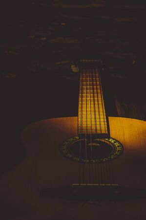 Acoustic guitar close-up in the dark, illuminated by a beam of light.の写真素材