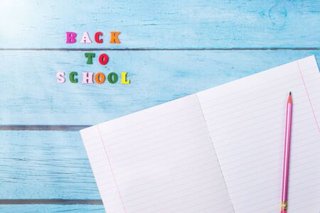 Layout of school supplies on a blue wooden background. Top view, sun rays from the side. Flat lay....
