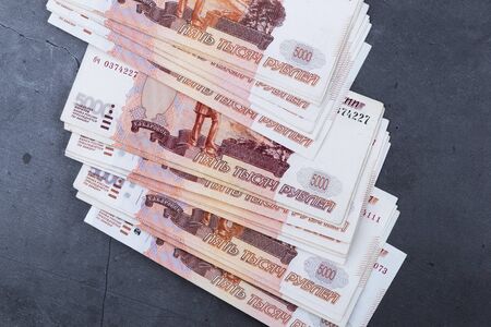Big stack of Russian money banknotes of five thousand rubles lying on a grey cement background