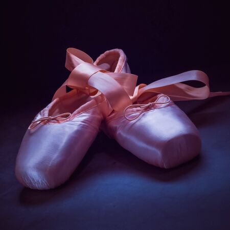 Pointe shoes ballet dance shoes with a bow of ribbons beautifully folded on a dark background