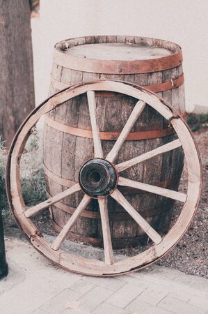 An old wooden cartwheel stands by a wooden barrel