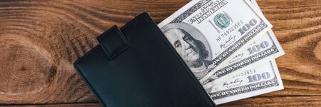 On wooden boards, textured wallet with one hundred dollar bills