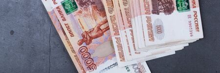 Big stack of Russian money banknotes of five thousand rubles lying on a grey cement background