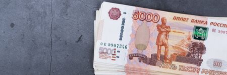 Big stack of Russian money banknotes of five thousand rubles lying on a grey cement background