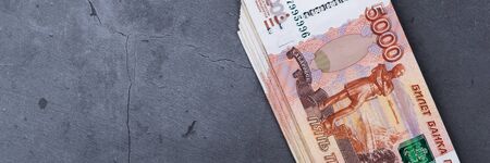 Big stack of Russian money banknotes of five thousand rubles lying on a grey cement backgroundの写真素材