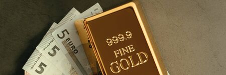 Gold metal ingot in ingots on the background of Euro banknotes