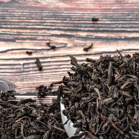 Dried tea is poured into a ceramic cup on a wooden plank tableの写真素材