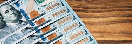 A row of cash hundred American banknotes on a wooden background