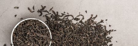 Dried tea is poured into a white ceramic cup on a gray textured background. View from above. Layoutの写真素材