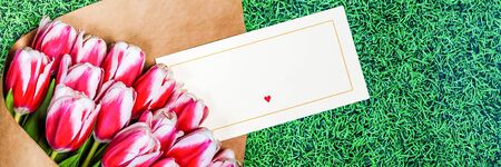 Bouquet of red tulips for a holiday women's day and valentine's day on a background of green grassの写真素材