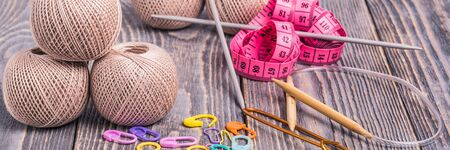 Balls of yarn, knitting needles, measuring tape and clips on wooden background.の写真素材