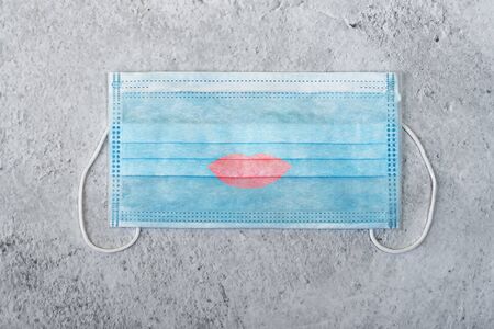 A medical mask with a drawn lips, kiss. A typical surgical mask to cover the mouth and nose. Concept...