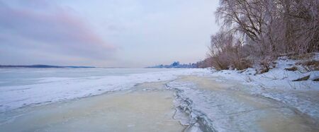 Winter landscape at dawn, riverbank of a frozen ice. Hanging tree branches, beautiful sky, large ice floes.の写真素材