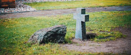 An ancient stone funeral cross and a tombstone on the burial ground near the wall of the old castle.の写真素材