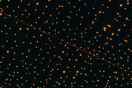 Many lightbulbs hanging on cable as garland decorative isolated on dark night sky backgroundの写真素材